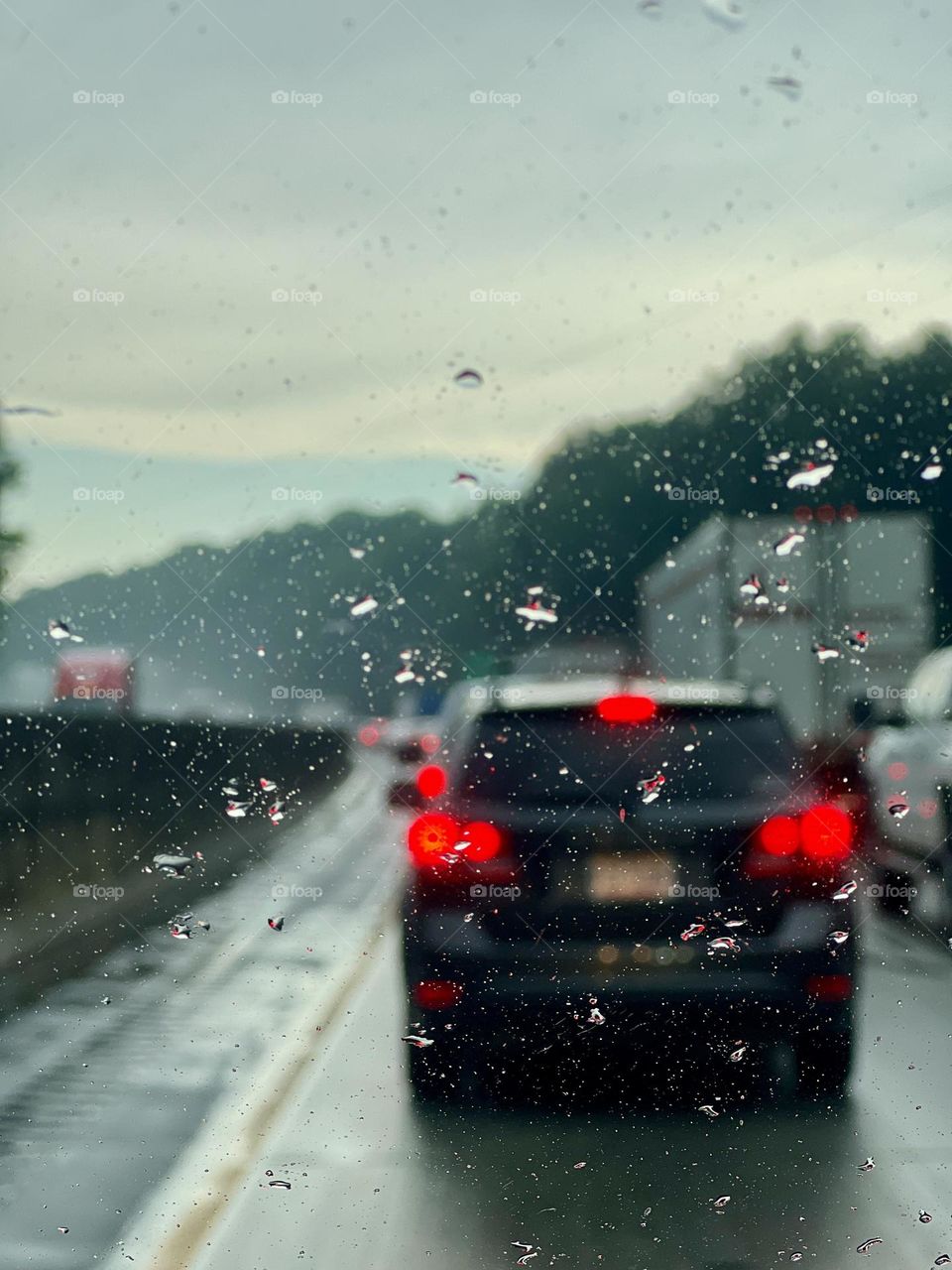 View from inside moving car on a rainy day, with lighter skies ahead in the distance 