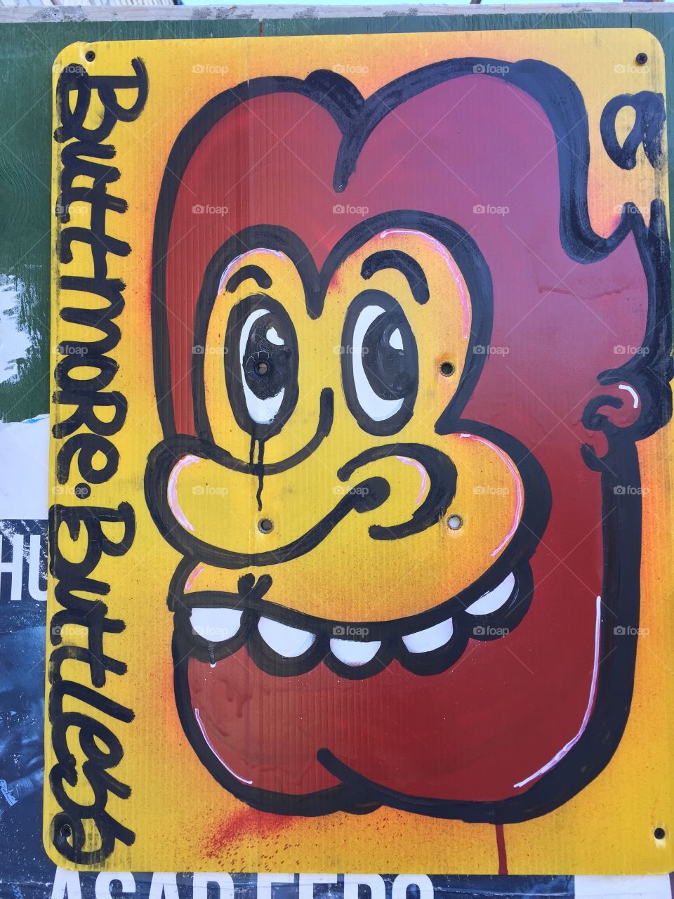 Yellow and brown graffiti sprayed on top of a construction citing of a lion/make smiling face showing humorous teeth and big eyes. Great retro style . Art at is finest . Graffiti illustration.