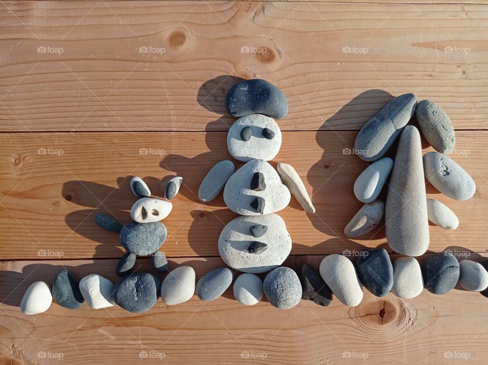 Winter scene out of stones. Stone figures of a snowman, a dog and a little tree.