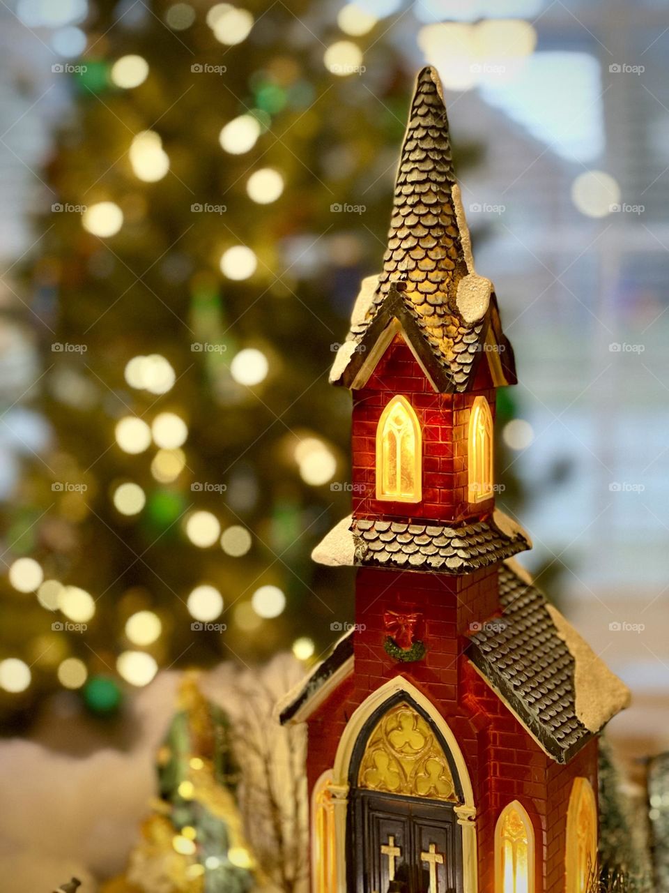 Upper portion gothic style country church tower steeple windows alight at Christmas time Christmas tree alight background blurred Bokeh room for text