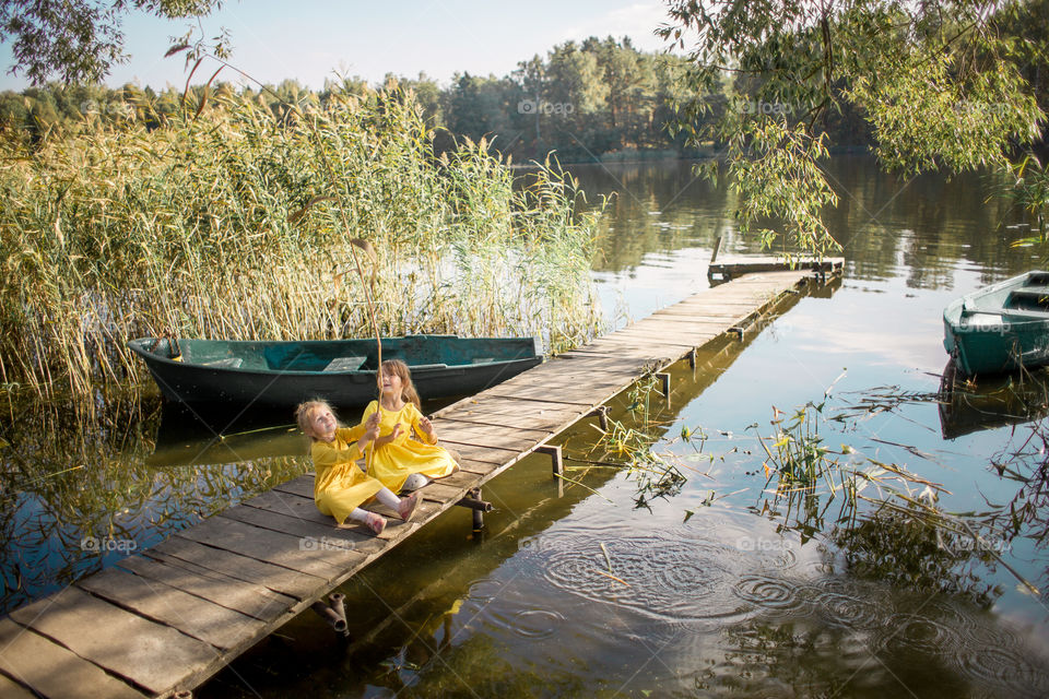 Little sisters playing near lake at autumn day 