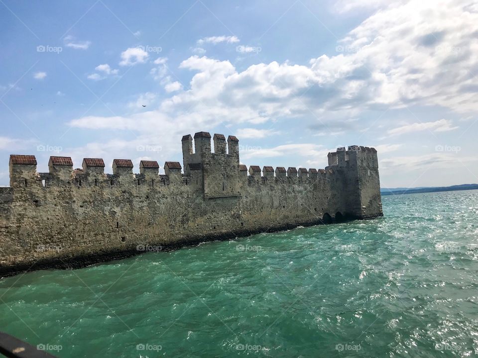 a wall on turquoise water , in the sky with many white clouds , there is sunshine . Summer weather is beautiful. There are many tourists coming here, I was fascinated by this landscape