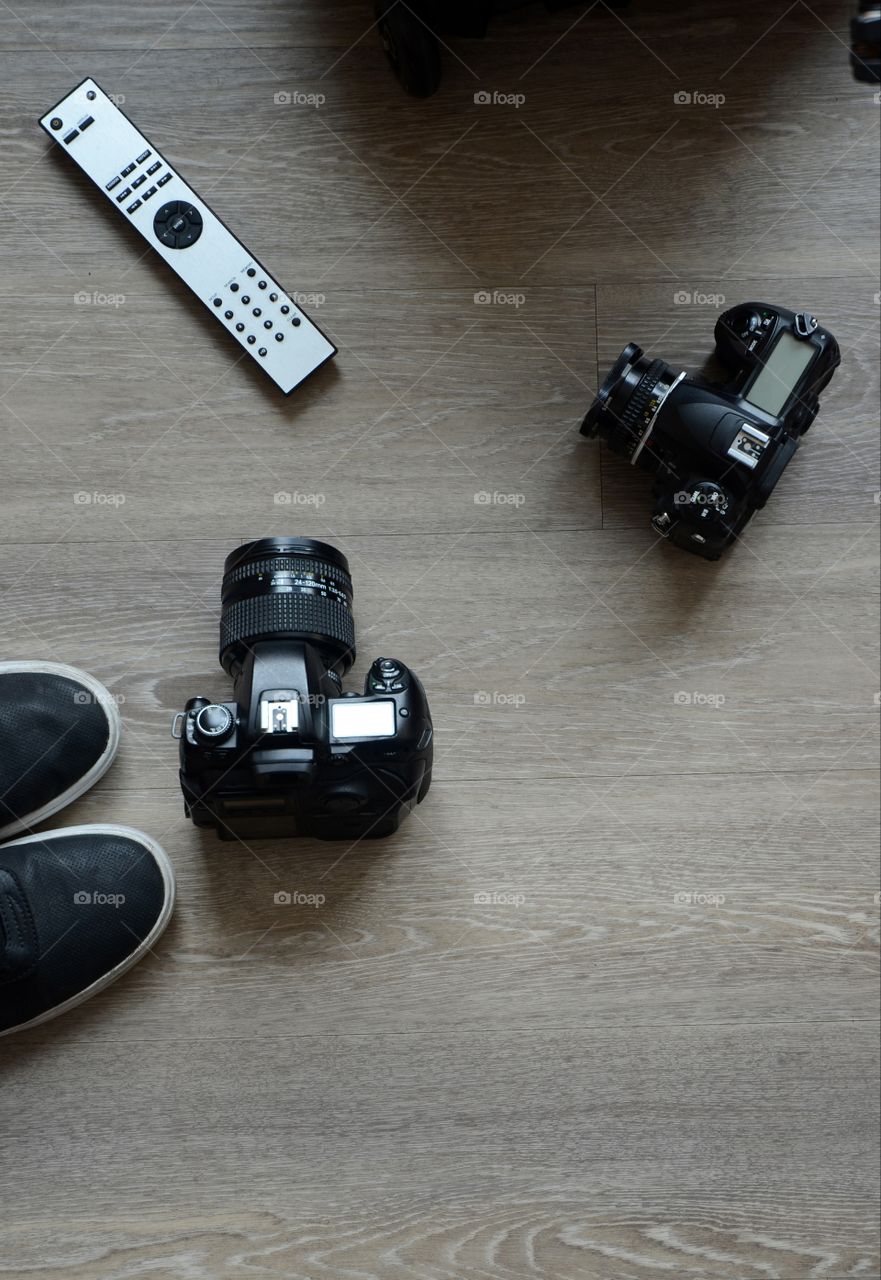 Professional cameras and a TV remote lay on an apartment floor.