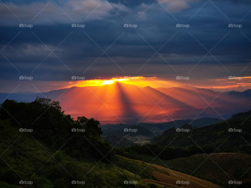 A sunburst sunset view from Doi Samer Dao in Nan, Thailand. The sun only has a little room to squeeze through between the clouds.