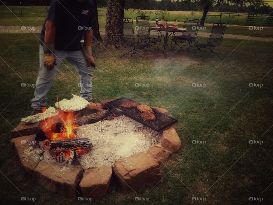 Man Cooking Steaks on an Open Rock Fire Pit