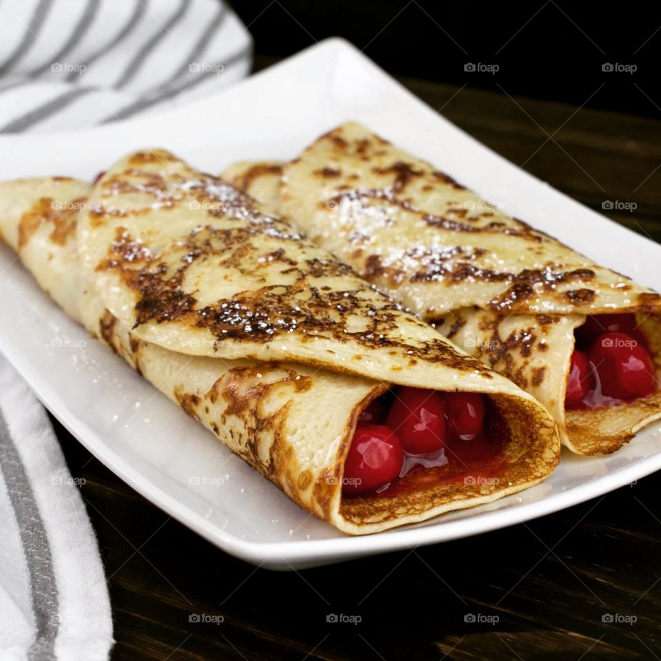 Crepes with cherry filling dusted with powdered sugar