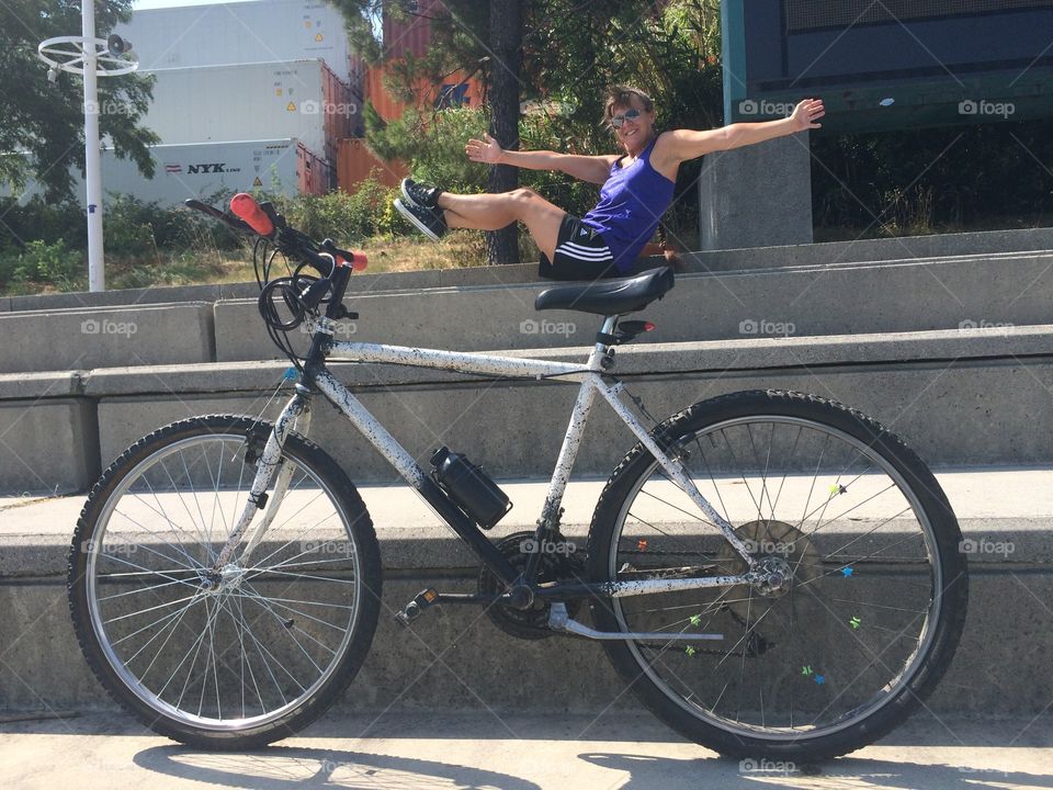 Man posing with stretched arm behind parked bicycle