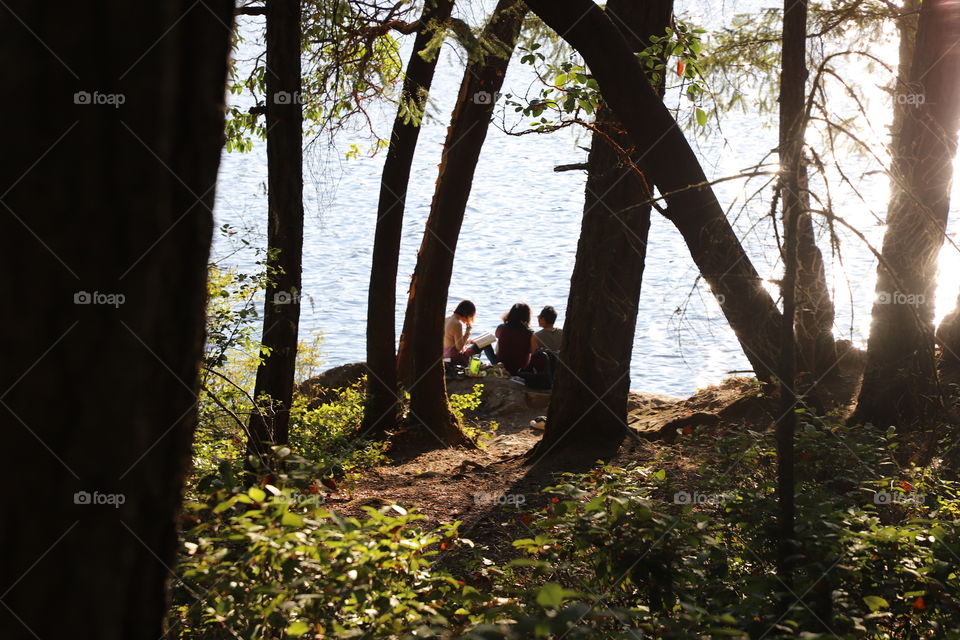 Friends by the lake on late afternoon enjoying the sunny spot