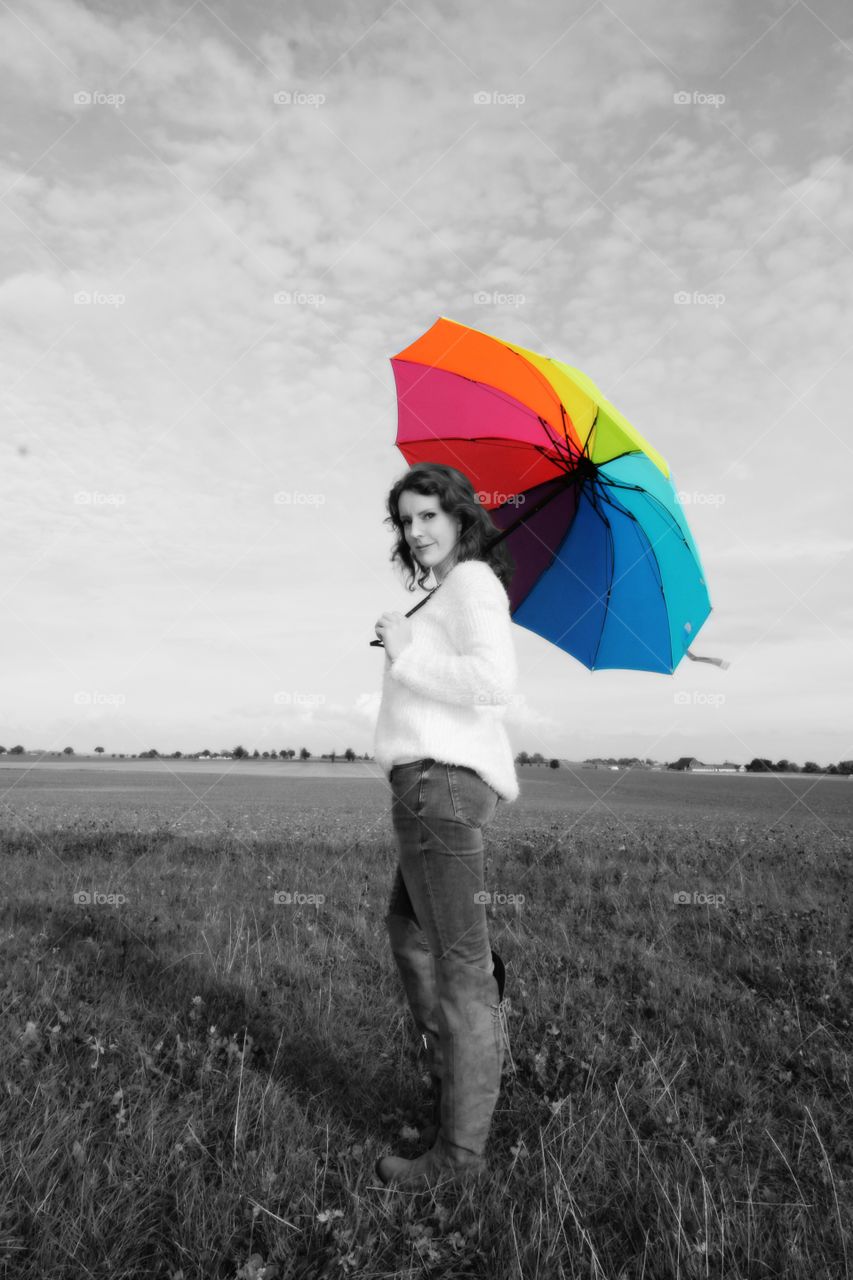 Woman standing in field with umbrella