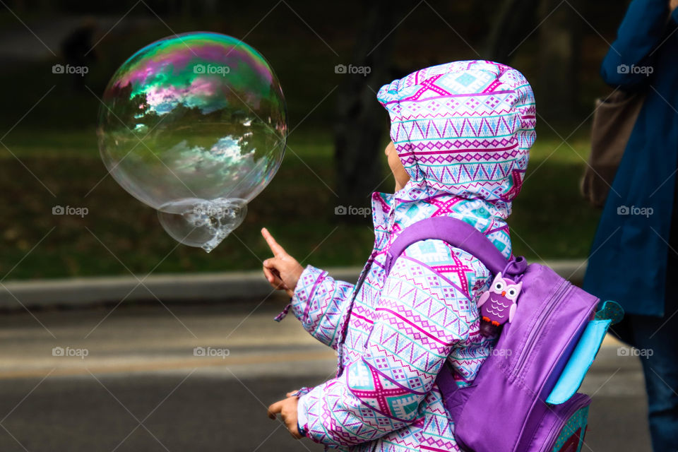 Child is about to touch a big soapy bubble