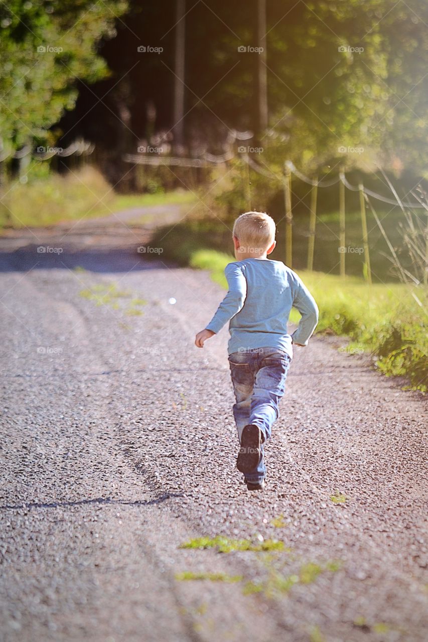 Rear view of little boy running in park