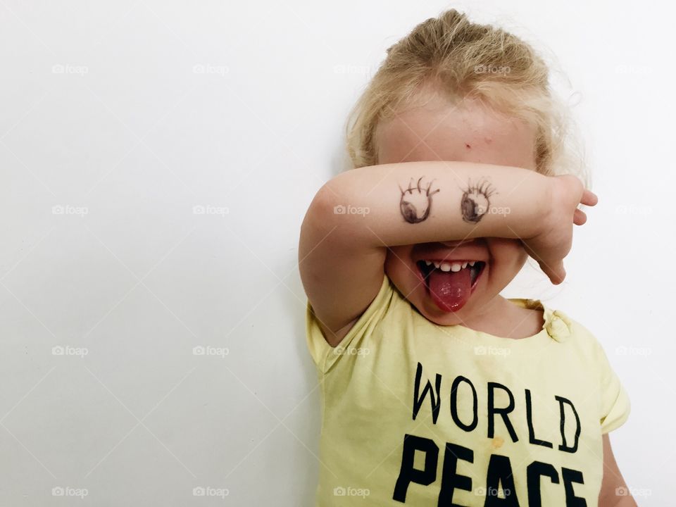 Close-up of girl with eyes drawn on hand