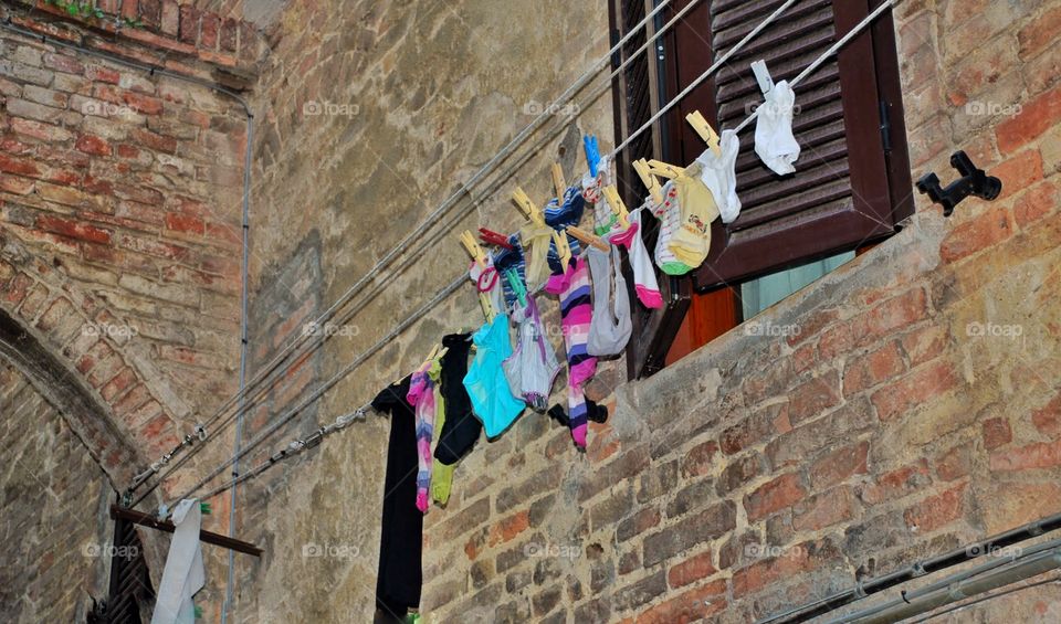 Out to dry. Colorful socks hang out on a laundry line outside a window in the Medeival village of Sienna
