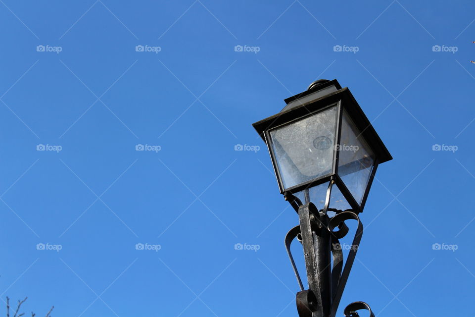 public street lamp with metal black ornaments and blue sky