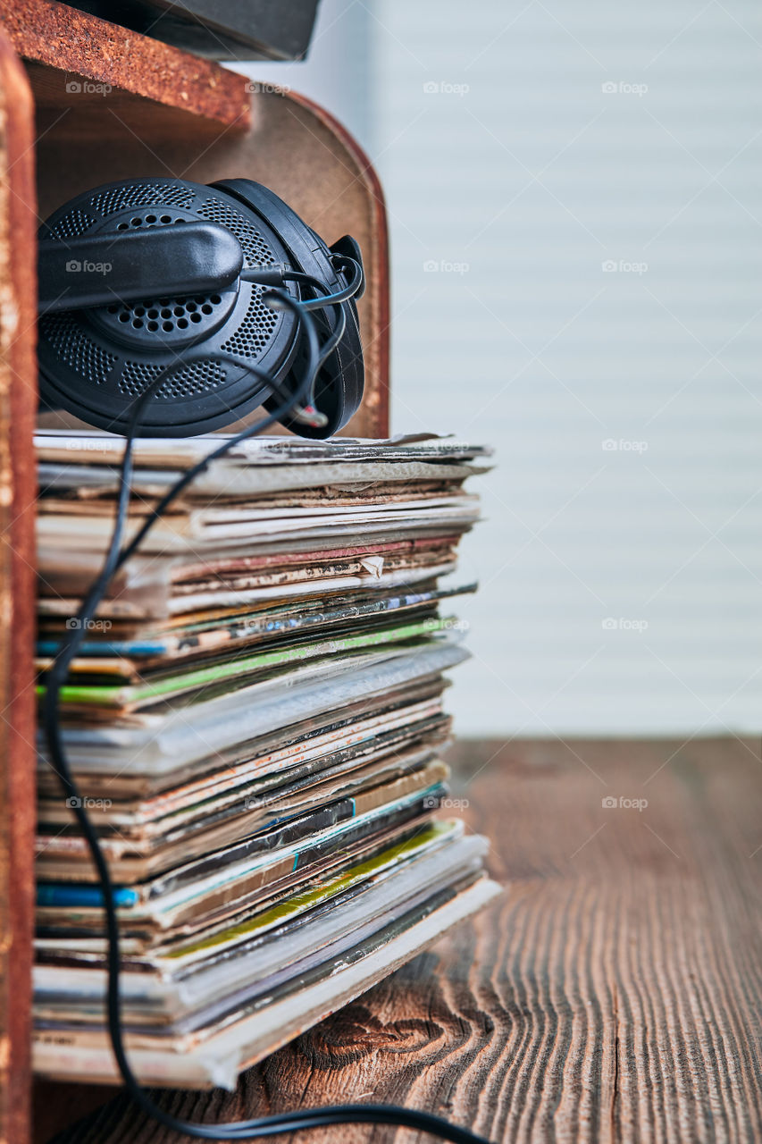 Stack of black vinyl records, turntable vinyl player and headphones. Classic stereo set. Candid people, real moments, authentic situations