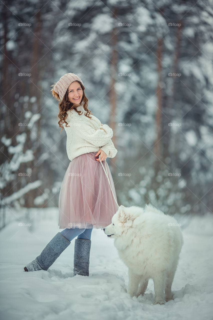 Young woman with Samoyed dog in winter park 