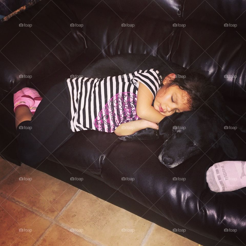 A little girl sleeping on sofa with dog