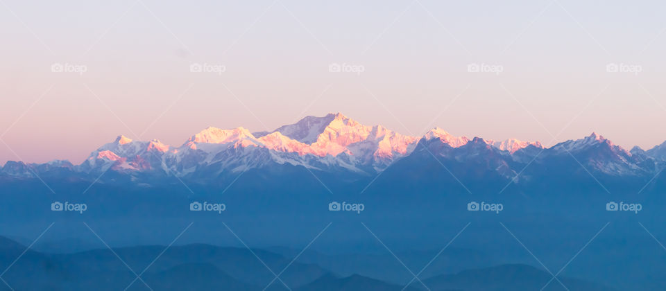 Panorama of majestic Mount Kanchendzonga range of himalayas at first sunrise from Tiger Hill. First ray of sun struck mountain starting beautiful day on entire nature around. Darjeeling, Sikkim, India