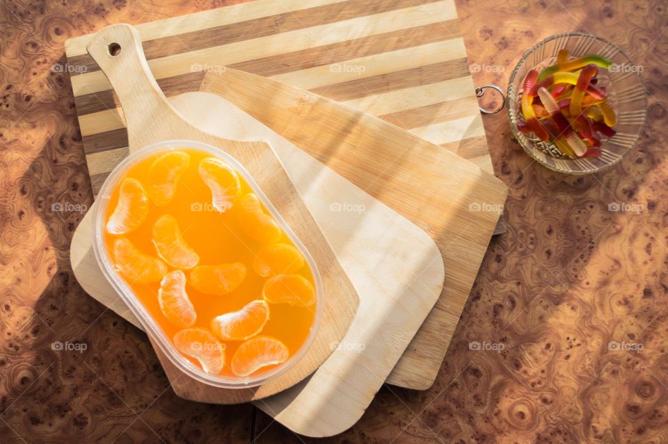 Delicious orange jelly with tangerine slices in a container and jelly worms.