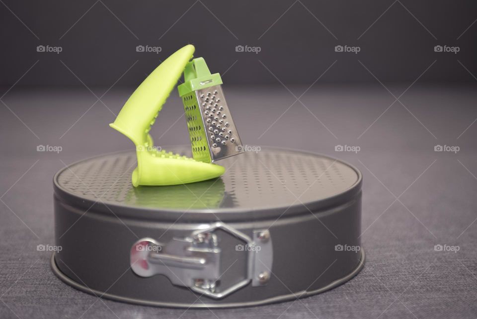 Miniature metal grater close-up. Abstract composition of metal kitchen items and silicone heat-resistant potholder.