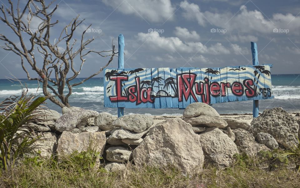 Sign with the colorful writing "Isla Mujeres" immersed in a typical Caribbean landscape.