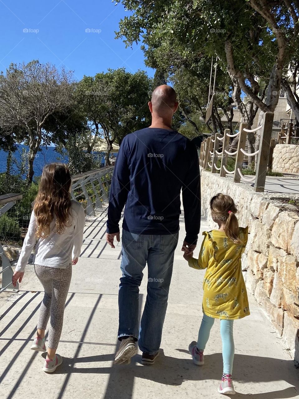 Father walking with daughters by the Adriatic Sea.