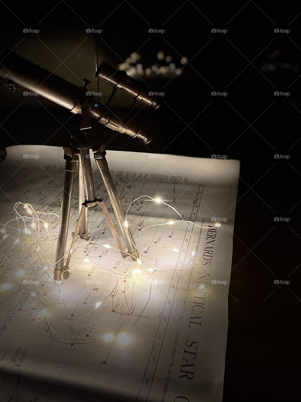 Vintage telescope on a vintage nautical star map with twinkling lights.