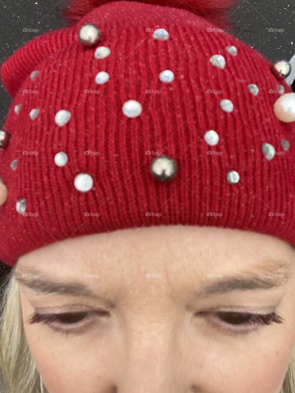 Me wearing L’Oréal Voluminous Mascara in “Deep Violet” on my lashes. On my lids is Bare Minerals eye color in “Queen Phyllis,” a gold-toned shade. On my head is a festive red hat given to me by a friend last Christmas. 
