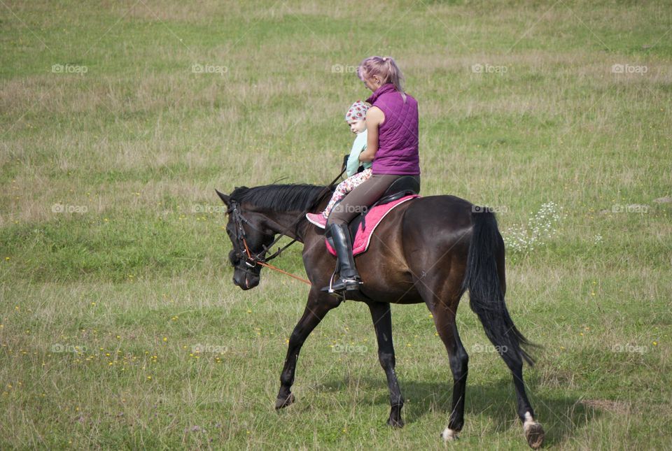 mom and daughter ride a horse