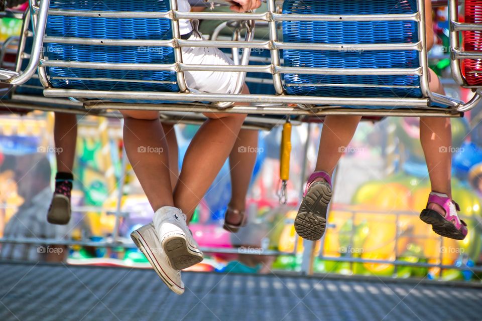 The legs of children from behind sitting on a merry-go-round at an amusement park