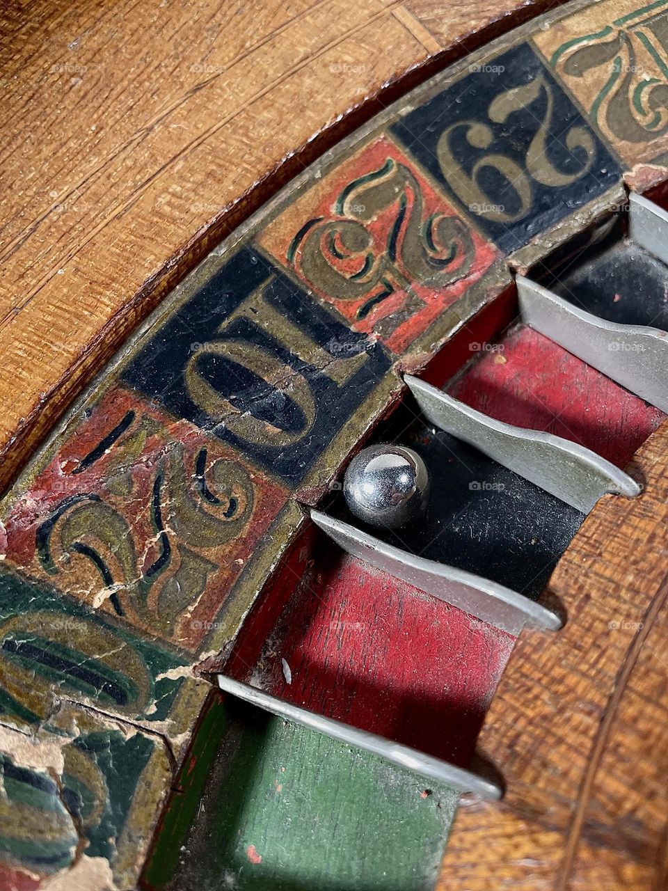 A closeup of an antique roulette wheel with distressed paint may be old but still ready to spin.