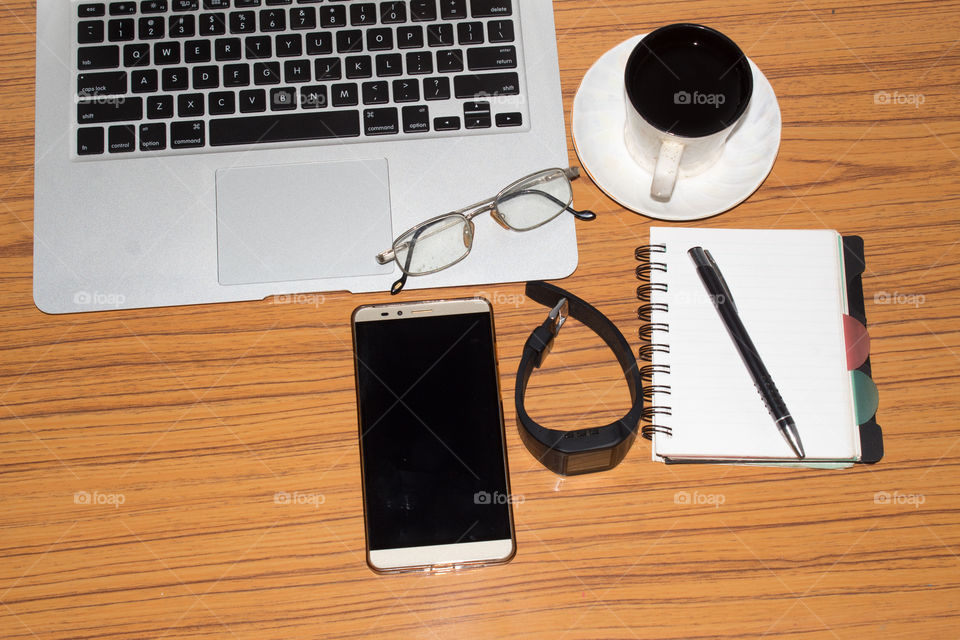 Desk with open notebook, wrist watch, eye glasses, pen and a cup of coffee. Top view with copy space. Business still life concept with office stuff on table. Education, working or planning concept