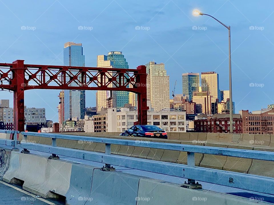 This is the LIC skyline seen from the pedestrian lane of the „Pulaski Bridge“ at „Newtown Creek“ in LIC, Queens on a beautiful Indian summer evening in 2023. The bridge connects „Greenpoint“, Brooklyn with „Queens“. Hypnotic Productions