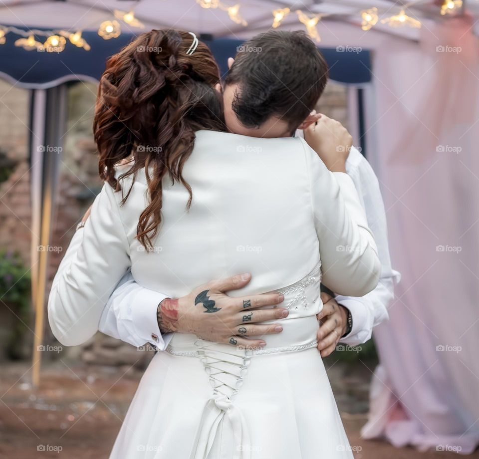 Newly married couple share their first dance, under a gazebo of lights and pink curtains