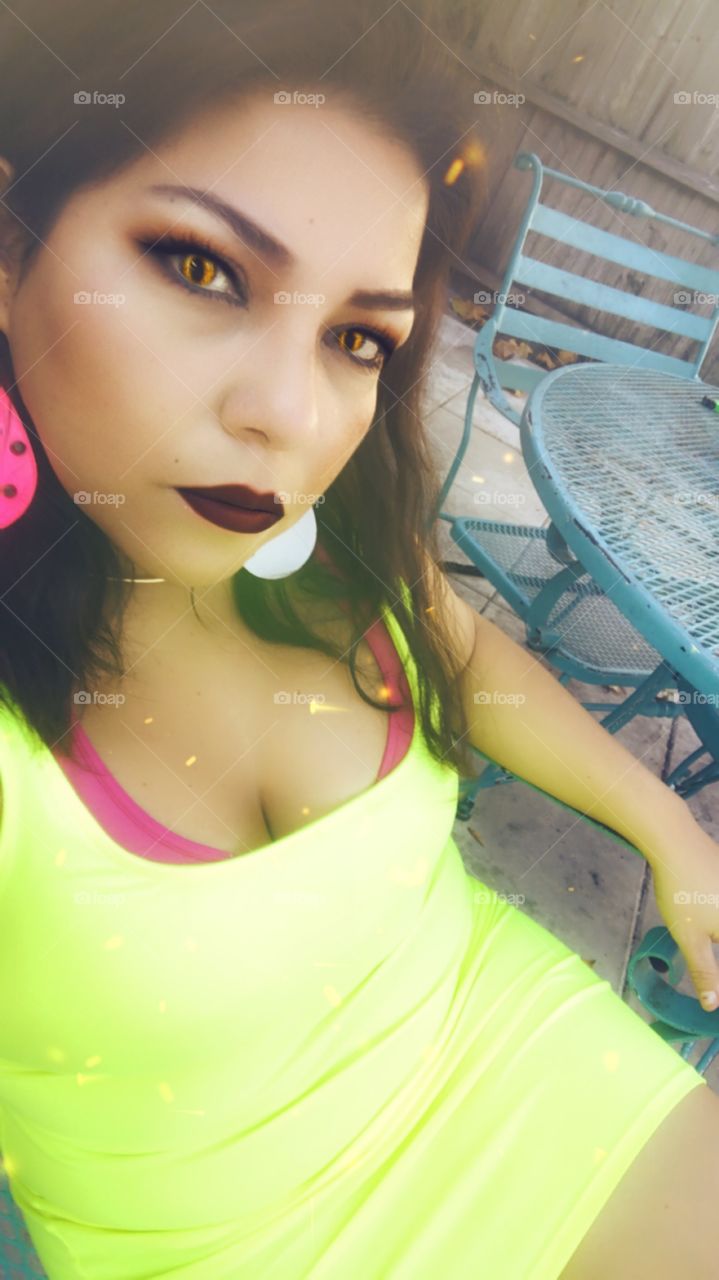 Spanish woman in Neon green  dress dark lips pink bra and earrings 