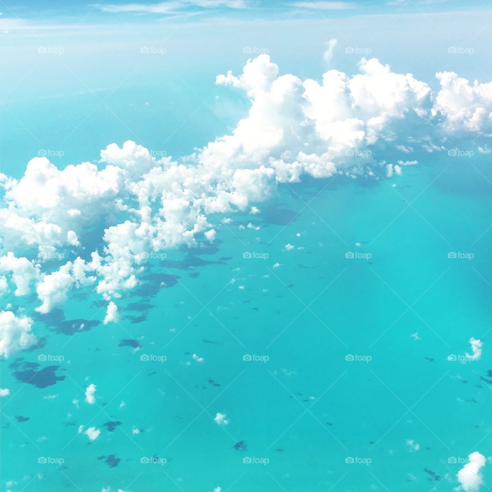 Aerial view of the clouds above a crystal clear tropical ocean