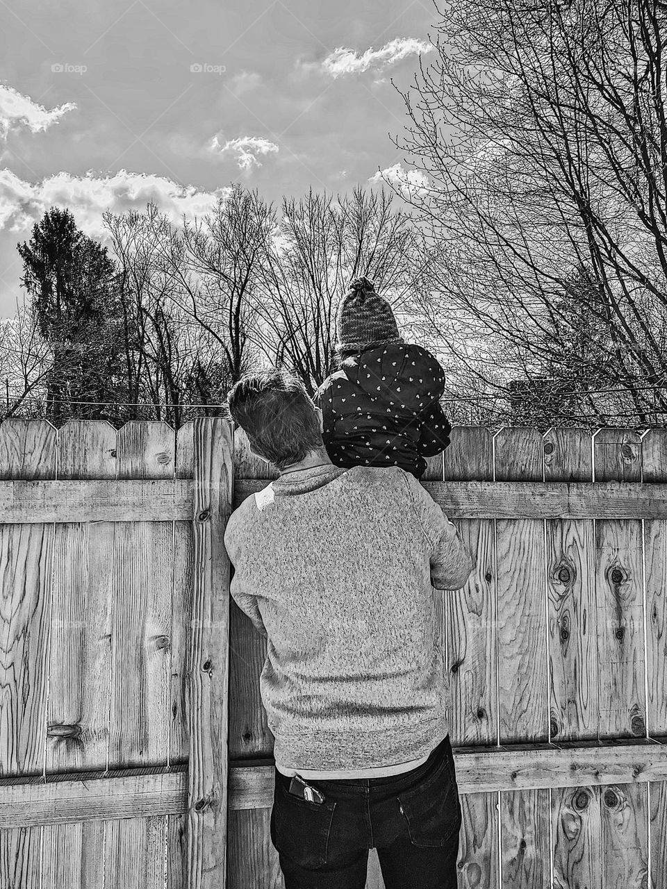 Daddy looks over fence with daughter, showing daughter the world, looking over the fence