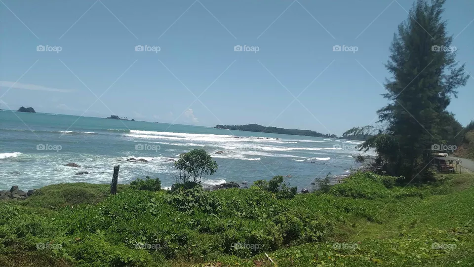 Sea view with amazing waves towards a beautiful beach plus amazing blue sky.