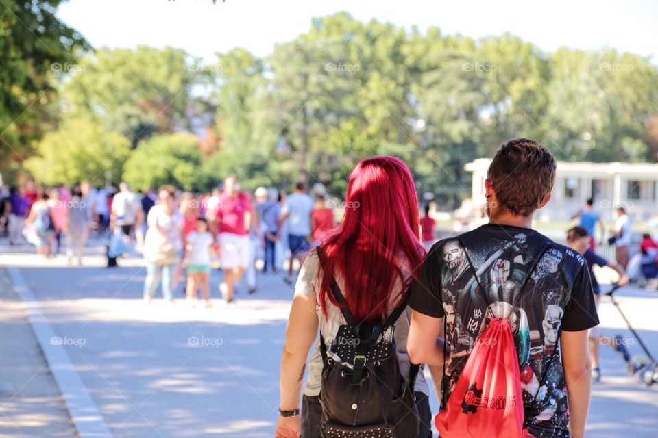 Beautiful red haired woman walking together with a man in a park on a summer day 