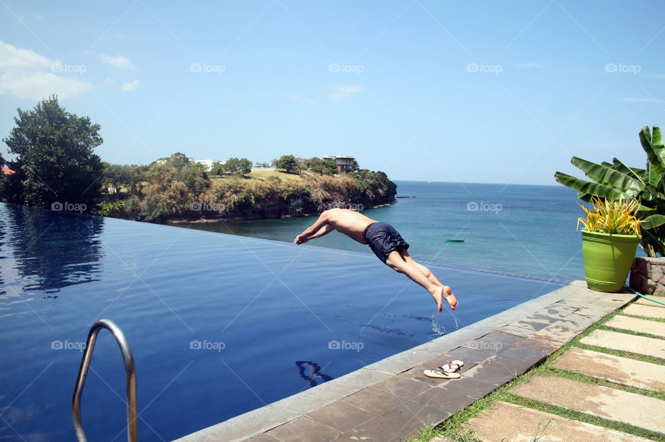 Man diving in infinity pool with an overlooking view