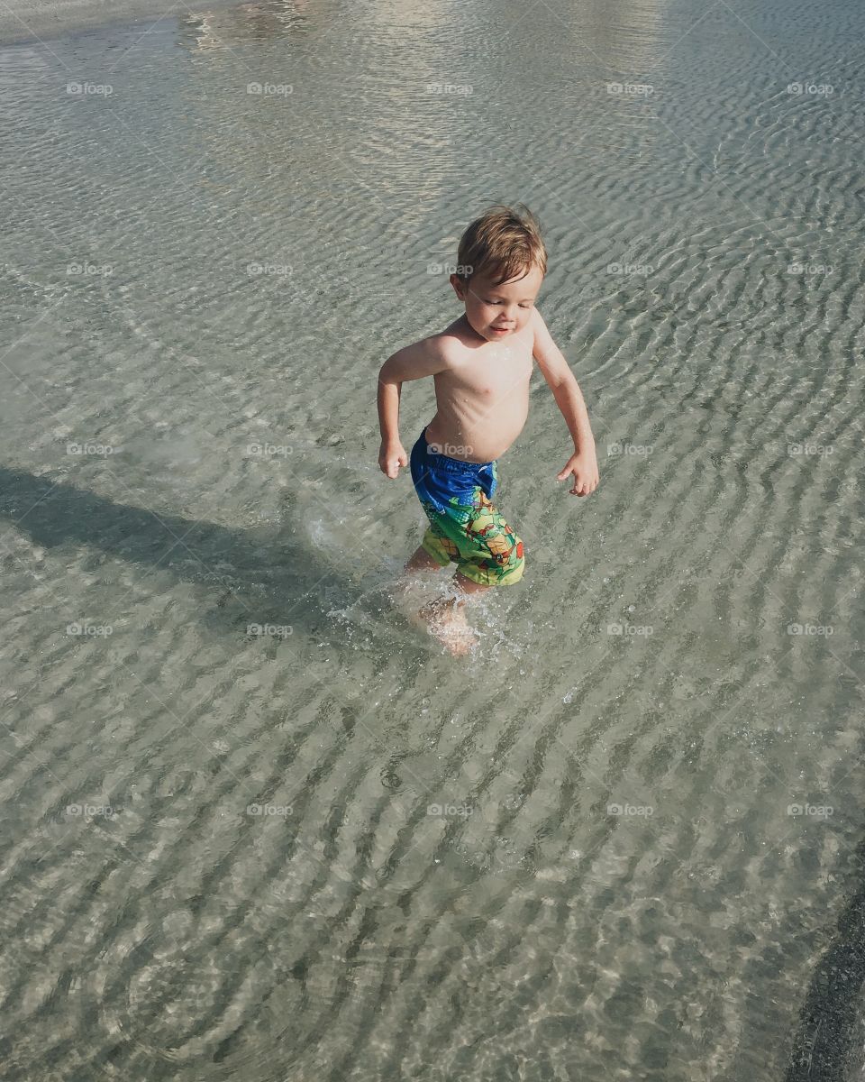 Child running through water in ocean