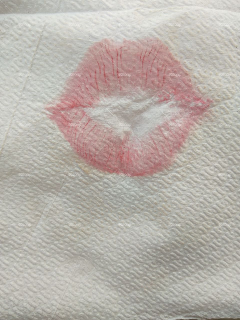 Close up of lip print with red lipstick on the napkin, lipstick kiss on white background.