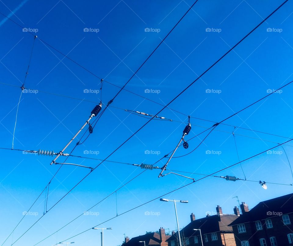 Overhead power lines at Mill Hill Broadway train station, London, against bright blue sky
