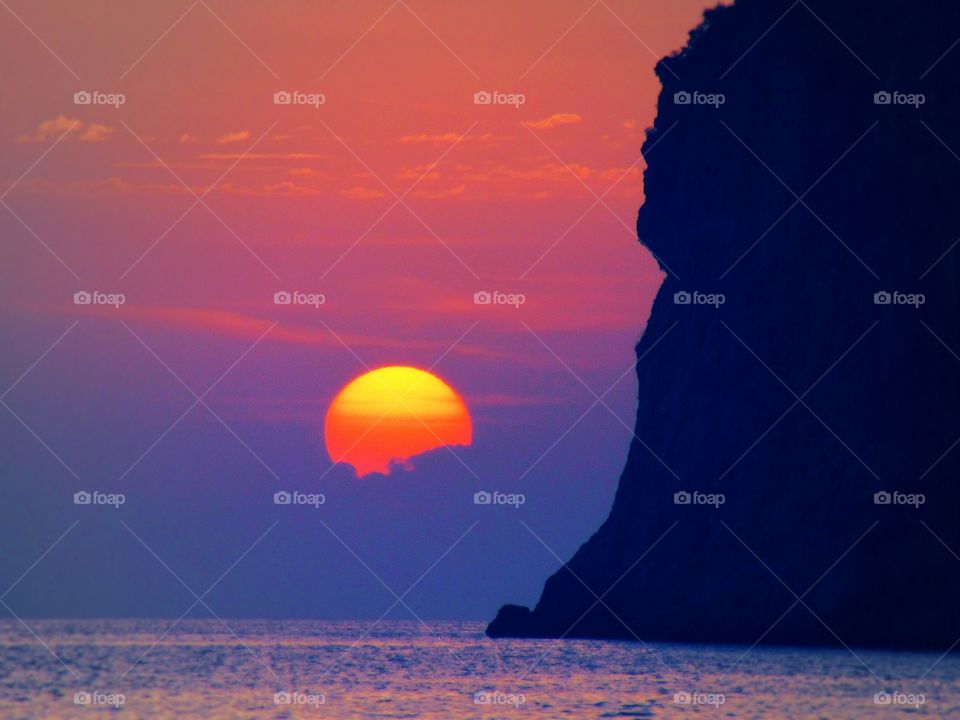 Silhouette of cliff in sea