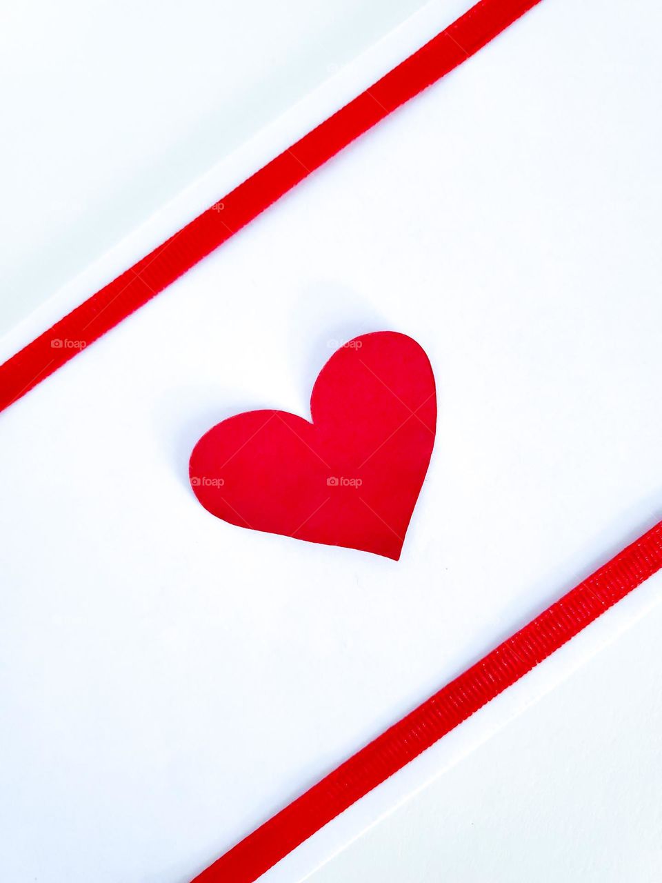 Red heart and two red stripe ribbons on a white background