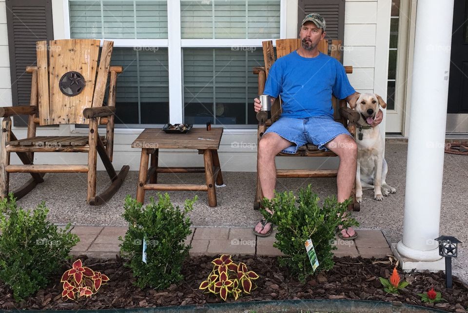 Man smoking cigar sitting on chair with his dog