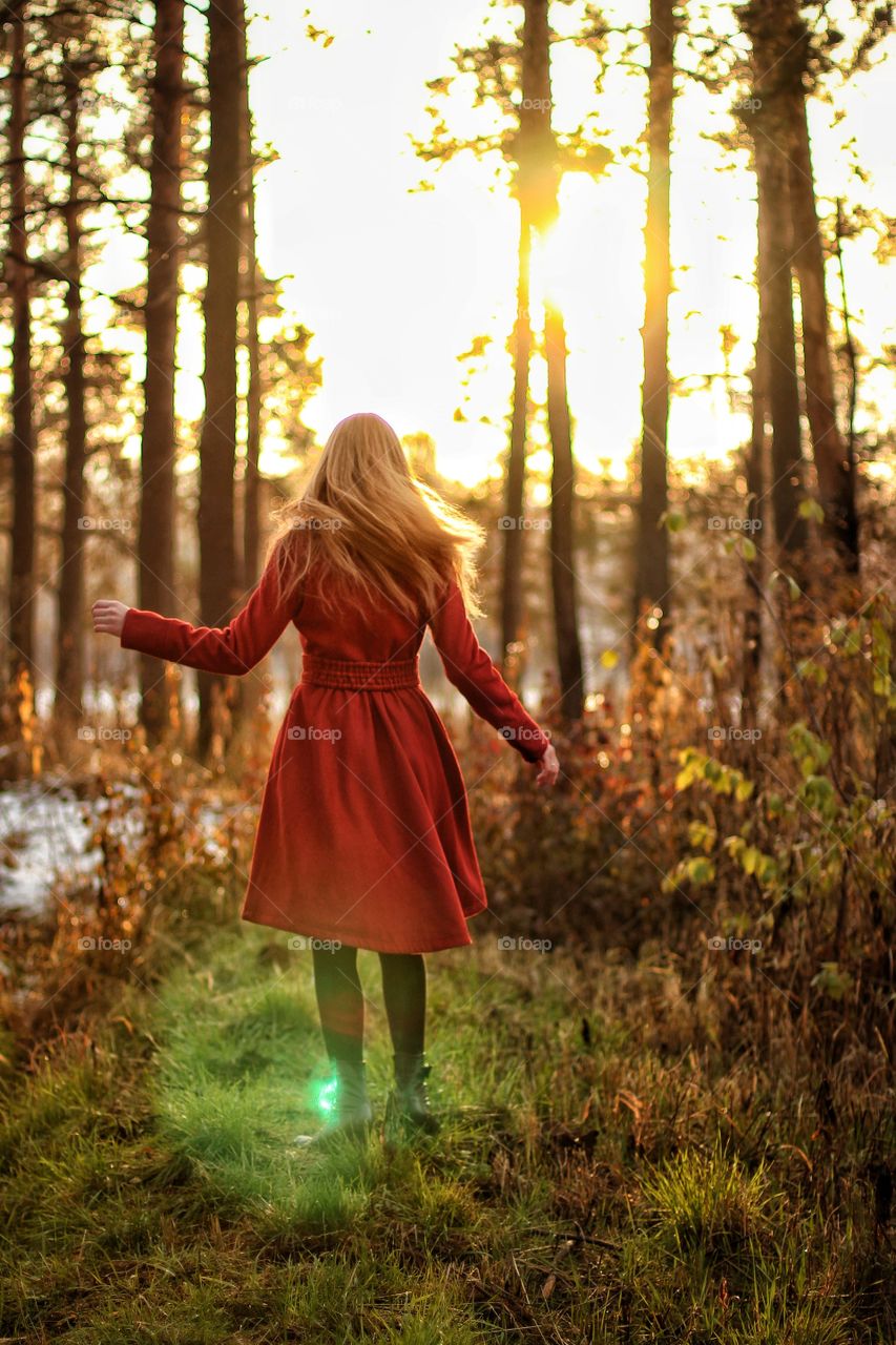Girl runs through the forest at sunset