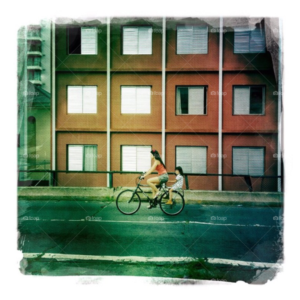 A woman and a girl in a bike on the street