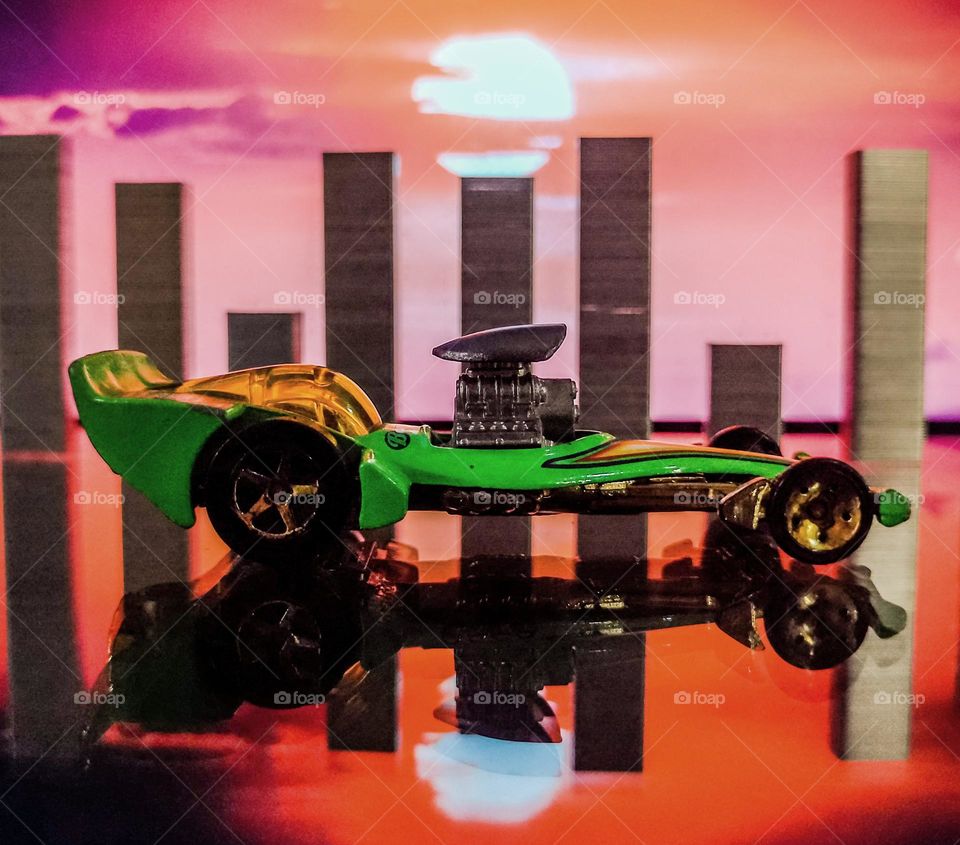 green formula one car toy, with a sunset in the background