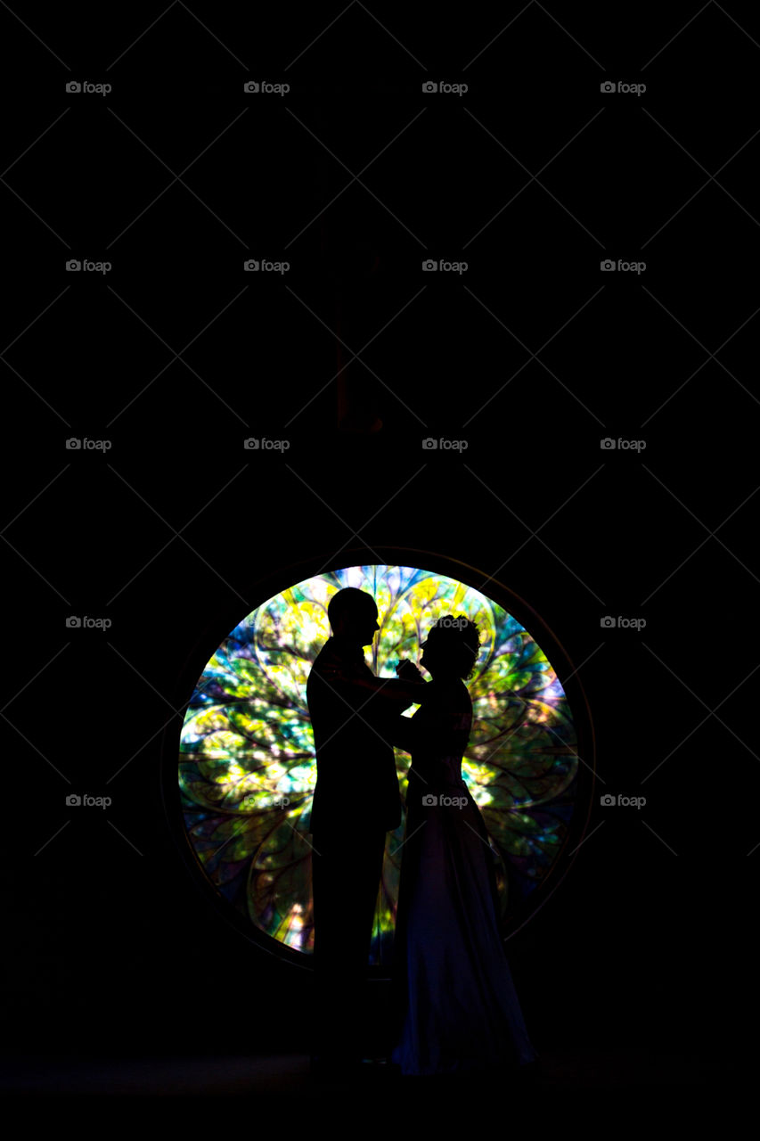 Silhouette dance of couple in front of stained glass window. Romantic image.